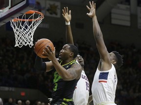 South Florida's LaQuincy Rideau, left, drives toward the basket past the arms of Connecticut's Sidney Wilson, behind center, and Eric Cobb, right, during the first half of an NCAA college basketball game, Sunday, March 3, 2019, in Storrs, Conn.