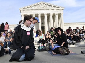 Alice Wisbiski, dressed as Supreme Court Associate Justice Ruth Bader Ginsburg, is joined by others as a group do exercises on the steps of the Supreme Court in Washington, Friday, March 15, 2019, to celebrate Ginsburg's upcoming birthday 86th birthday.