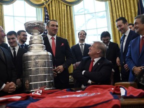 President Donald Trump, seated center, listens as Washington Capitals Alex Ovechkin, fourth from left, speaks during the teams visit to the Oval Office of the White House in Washington, Monday, March 25, 2019, to honor the 2018 Stanley Cup Champion Washington Capitals hockey team. Capitals owner Ted Leonsis, right, and NHL Commissioner Gery Bettman, left, and other members of the team listen.