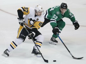 Pittsburgh Penguins center Sidney Crosby (87) and Dallas Stars defenseman Esa Lindell (23) skate for the puck during the first period of an NHL hockey game in Dallas, Saturday, March 23, 2019.
