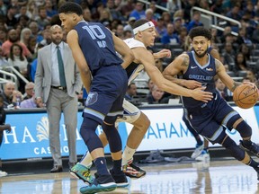 Memphis Grizzlies guard Tyler Dorsey (22) dribbles by Orlando Magic forward Aaron Gordon, center, as Memphis Grizzlies forward Ivan Rabb (10) sets a pick on Gordon during the first half of an NBA basketball game in Orlando, Fla., Friday, March 22, 2019.