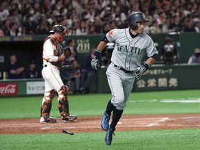 Seattle Mariners' Ichiro Suzuki flies out to center as Yomiuri Giants catcher Seiji Kobayashi stands at home in the second inning of their pre-season exhibition baseball game at Tokyo Dome in Tokyo Sunday, March 17, 2019.