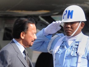 Brunei Sultan Hassanal Bolkiah (L) is greeted upon his arrival at Ngurah Rai International Airport in Denpasar on the Indonesian resort island of Bali to take part in the Asia-Pacific Economic Cooperation (APEC) summit on October 6, 2013.