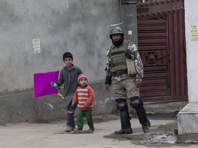 Kashmiri children walk past an Indian paramilitary soldier during a security lockdown in downtown Srinagar, Indian controlled Kashmir, Friday, March 1, 2019. India has banned Jama'at-e-Islami, a political-religious group in Kashmir, in a sweeping and ongoing crackdown against activists seeking the end of Indian rule in the disputed region amid the most serious confrontation between India and Pakistan in two decades.