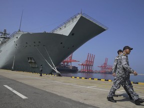 Australian naval officers walk past the HMAS Canberra, one of four Royal Australian Navy ships visiting Sri Lanka as part of defense corporation between the two countries, in Colombo, Sri Lanka, Friday, March 29, 2019. Australia says its armed forces have no qualms about working with Sri Lankan security forces accused of grave human rights violations during the country's civil war, but those allegations must be taken seriously and investigated.