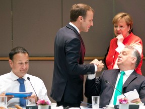 In this Friday, June 29, 2018 file photo French President Emmanuel Macron, center, greets Hungarian Prime Minister Viktor Orban, right, during a breakfast meeting at an EU summit in Brussels.