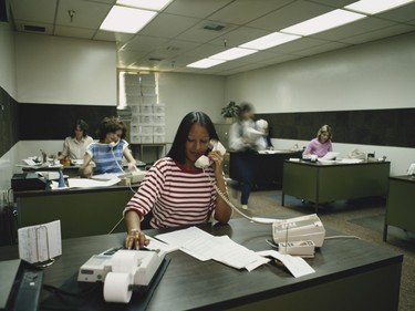 A woman taking calls in the 1980s, in a bold colour and stripe.