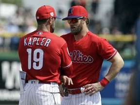 Philadelphia Phillies manager Gabe Kapler (19) talks to Bryce Harper before a spring training baseball game against the Tampa Bay Rays Monday, March 11, 2019, in Clearwater, Fla.