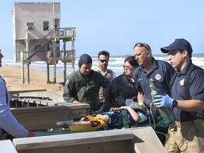 In this Wednesday, March 20, 2019 photo, rescue workers carry an injured child off the beach at Ormond-by-the-Sea, Fla. The Florida Highway Patrol says a sport-utility vehicle driven by 82-year-old William Johnson ripped through a wooden barrier separating a parking lot from the beach and hit four children in the sand.
