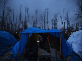 Jacinta Wheeler checks her phone in the entryway of her tent in the backyard of a home where she's living after becoming homeless from Hurricane Michael in Youngstown, Fla, Wednesday, Jan. 23, 2019. Wheeler, whose apartment was damaged by the hurricane, has been working construction jobs and helping make repairs to neighbors' properties while she stays in her tent. "Everybody wants the American dream," the Trinidad native said. "If this is the dream, I don't want it."