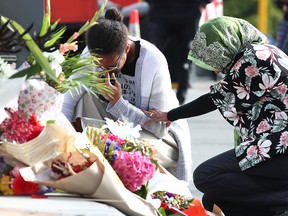Women lay flowers near the Al-Noor Mosque in Christchurch, New Zealand, on March 16, 2019, in tribute to the 49 people who were killed and 20 seriously injured in gun attacks on it and another mosque the day before.