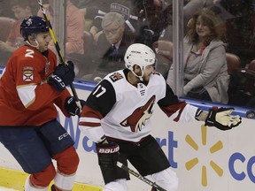 Arizona Coyotes center Alex Galchenyuk (17) stops the puck with his glove as Florida Panthers defenseman Josh Brown (2) follows during the first period of an NHL hockey game on Thursday, March 21, 2019, in Sunrise, Fla.