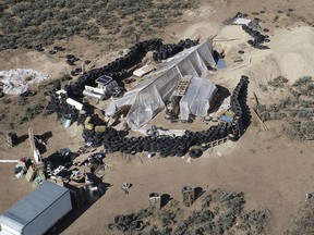 FILE - This Aug. 10, 2018, file photo shows a ramshackle compound in the desert area of Amalia, N.M. The five men and women found living in a ramshackle compound in northern New Mexico where a boy was found dead last year have been indicted on federal charges related to terrorism, kidnapping and firearms violations. The U.S. attorney's office in New Mexico announced the superceding indictment Thursday, March 14, 2019.
