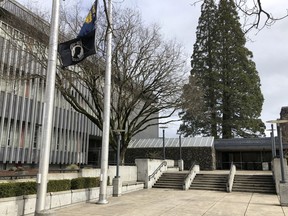 In this photo taken March 7, 2019, flags, including a POW/MIA flag, flap in a breeze in front of the Lane County Circuit Court building where the Veterans Treatment Court is held in Eugene, Ore. Military veterans who are struggling with addiction and have tangled with the law are being given a second chance in an Oregon courtroom. But the Veterans Treatment Court and 40 other specialty courts in Oregon are at risk of losing their federal funding unless the state enforces federal immigration policies.