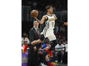Atlanta Hawks guard Trae Young (11) saves a ball from going out of bounds as Philadelphia 76ers head coach Brett Brown stands on the sideline during the first half of an NBA basketball game Saturday, March 23, 2019, in Atlanta.