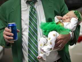 Joey Homans holds his 3-month-old granddaughter Caroline Homans in one hand and a beer in the other before the start of the Savannah St. Patrick's Day parade, Saturday, March 16, 2019, in Savannah, Ga. Started by Irish immigrants to Georgia's oldest city 195 years ago, the March parade has ballooned into a sprawling street party that's the No. 1 tourist draw for Savannah.