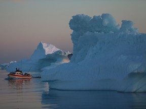 A fishing boat navigates past icebergs that broke off from the Jakobshavn Glacier on July 23, 2013 in Ilulissat, Greenland.