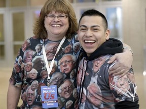 Cristian Gomez of Lincoln, Neb., right, and Lisa Heineman, who have never met, pose for a photo while wearing Bernie Sanders shirts, ahead of a Sanders rally in Council Bluffs, Iowa, Thursday, March 7, 2019.