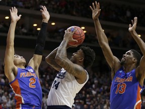 Nevada's Jordan Caroline (24) shoots between Florida's Andrew Nembhard (2) and Kevarrius Hayes (13) during the first half of a first round men's college basketball game in the NCAA Tournament in Des Moines, Iowa, Thursday, March 21, 2019.