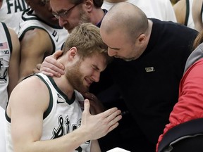 A medical personnel took talks to Michigan State's Kyle Ahrens, left, as Ahrens was the taken out of the court for injury during the first half of an NCAA college basketball championship game against Michigan in the Big Ten Conference tournament, Sunday, March 17, 2019, in Chicago.