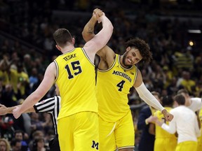 Michigan's Jon Teske (15) and Isaiah Livers (4) celebrate during the second half of an NCAA college basketball championship game against Michigan State in the Big Ten Conference tournament, Sunday, March 17, 2019, in Chicago.
