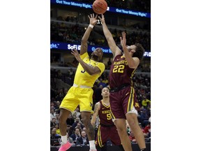 Michigan's Zavier Simpson (3) takes a shot over Minnesota's Gabe Kalscheur (22) during the first half of an NCAA college basketball game in the semifinals of the Big Ten Conference tournament, Saturday, March 16, 2019, in Chicago.