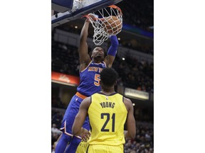 New York Knicks' Dennis Smith Jr. (5) dunks as Indiana Pacers' Thaddeus Young (21) watches during the first half of an NBA basketball game Tuesday, March 12, 2019, in Indianapolis.