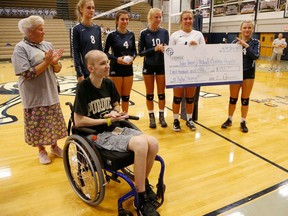 FILE - In this Sept. 4, 2018, file photo, Central Catholic players present Tyler Trent, foreground, with a check to benefit Riley Children's Hospital before meeting Lafayette Jeff in a high school volleyball game in Lafayette, Ind. A memorial gate leading to the student section entrance of Purdue University's football stadium will be built to honor Trent, the school's superfan and cancer activist who died in January.