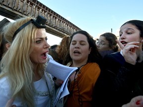 A member of the liberal Jewish religious movement Women of the Wall wearing 'Tefillin' or phylacteries (small black leather boxes containing scrolls of parchment inscribed with Torah verses), and 'Tallit' (traditional Jewish prayer shawls for men), argues with Ultra Orthodox Jewish girls interrupting her prayers at the Western Wall in the Old City of Jerusalem on March 8, 2019.