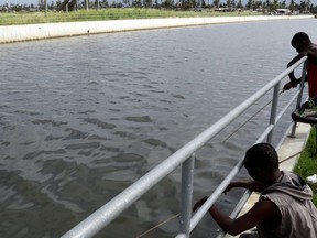 Fishermen fish in a drainage canal in Beira Mozambique, Sunday March 24, 2019. The canal is part of a newly-completed anti flooding system meant to protect the city against from rising waters. Long before Cyclone Idai roared in and tore Beira apart the mayor dreamed of protecting his people from adverse weather conditions.