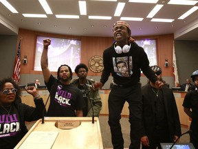 FILE - In this Tuesday, March 27, 2018 file photo, Stevante Clark stands on a desk as he shouts the name of his brother Stephon Clark, who was fatally shot by police a week earlier, during a meeting of the Sacramento City Council in Sacramento, Calif. Prosecutors are expected to announce Saturday, March 1 whether two police officers will face charges in last year's fatal shooting in Sacramento of an unarmed black man that generated nationwide protests.