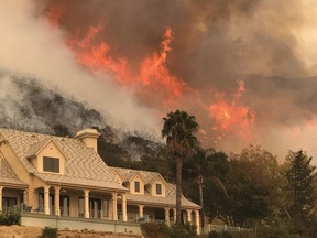 FILE - In this Thursday, Dec. 14, 2017, file photo provided by the Santa Barbara County Fire Department, shows flames from a back firing operation underway rise behind a home off Ladera Ln near Bella Vista Drive in Santa Barbara, Calif. An investigation has determined that one of the largest and most destructive fires in California history was sparked by power lines coming into contact during high winds. The Ventura County Fire Department says Wednesday that the contact ignited dry brush on December 4, 2017 and eventually blackened more than 440 square miles (1,139 square kilometers). The Thomas fire destroyed more than a thousand structures in Ventura and Santa Barbara counties and resulted in the deaths of two people.