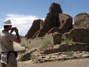 FILE - In this Aug. 10, 2005, file photo, tourist Chris Farthing from Suffolks County, England, takes a picture while visiting Chaco Culture National Historical Park in northwestern New Mexico. Native American leaders are banding together to pressure U.S. officials to ban oil and gas exploration around a sacred tribal site that features massive stone structures and other remnants of an ancient civilization. Tribes are gathering Thursday, March 21, 2019, to face the Trump administration's pro-drilling stance as they push for further protections surrounding Chaco Culture National Historical Park. Federal officials are revamping the management plan for the area around the world heritage site in New Mexico.