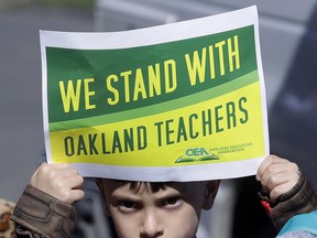 FILE - In this Feb. 21, 2019 file photo, a student holds up a sign while marching with parents, teachers and supporters outside of Manzanita Community School in Oakland, Calif. Striking teachers in Oakland are expected to vote Sunday, March 3, 2019 on a contract deal aimed at ending a seven-day walkout. The Oakland Education Association postponed the vote by a day after announcing earlier it would happen Saturday. The 3,000 teachers walked off the job Feb. 21, effectively shutting the city's 86 schools to demand higher pay, smaller classes and more school resources.