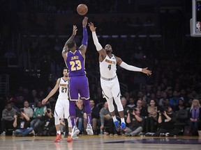 Los Angeles Lakers forward LeBron James (23) shoots as Denver Nuggets forward Paul Millsap, right, defends while guard Jamal Murray watches during the first half of an NBA basketball game Wednesday, March 6, 2019, in Los Angeles.