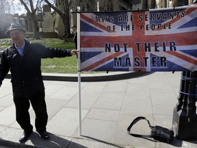 A campaigner holds a banner outside Parliament in London, Monday, March 25, 2019. British Prime Minister Theresa May is under intense pressure Monday to win support for her Brexit deal to split from Europe.