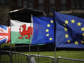 A Welsh flag, second left, placed by protestors who support Britain remaining in the European Union is blown in the wind next to a Union flag, at left, and two European flags near the Houses of Parliament in London, Tuesday, March 5, 2019. The National Assembly for Wales and the Scottish Parliament are both due to vote later Tuesday on motions declaring opposition to British Prime Minister Theresa May's Brexit deal and declare their opposition a no-deal Brexit.