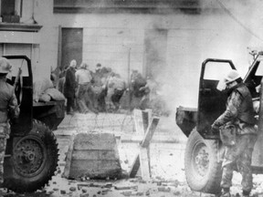 FILE - In this Jan. 30, 1972 file photo, soldiers take cover behind their sandbagged armoured cars in Londonderry, Northern Ireland. A former British soldier is set to be prosecuted in connection with the deaths of two civil rights protesters in Northern Ireland more than 40 years ago, part of an event known as Bloody Sunday. (PA via AP, File)