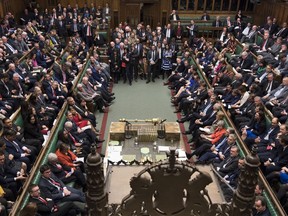 Britain's Prime Minister Theresa May sits on front bench right, orange jacket, facing a packed parliament Tuesday March 12, 2019. May keeps going, declining to resign, despite two successive parliamentary defeats of historic proportion and she is still pushing for her Brexit agreement, despite ample evidence that Parliament won't support it.