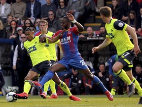 Huddersfield Town's Juninho Bacuna, left, and Crystal Palace's Michy Batshuayi tussle for the ball during the English Premier League soccer match between Crystal Palace and Huddersfield at the Selhurst Park stadium, London. Saturday, March. 30, 2019