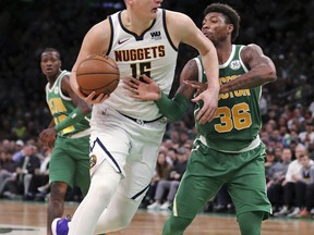 Denver Nuggets center Nikola Jokic (15) drives to the basket against Boston Celtics guard Marcus Smart (36) during the second half of an NBA basketball game in Boston, Monday, March 18, 2019.