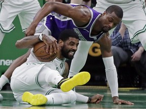 Boston Celtics guard Kyrie Irving, bottom, steals the ball from Sacramento Kings forward Harrison Barnes in the first half of an NBA basketball game, Thursday, March 14, 2019, in Boston.