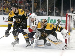 Florida Panthers left wing Jonathan Huberdeau (11) works for a position between Boston Bruins defenseman Brandon Carlo (25) and goaltender Tuukka Rask (40) in front of the goal during the first period of an NHL hockey game, Thursday, March 7, 2019, in Boston.