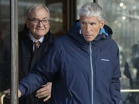 William "Rick" Singer, front, founder of the Edge College & Career Network, exits federal court in Boston on Tuesday, March 12, 2019, after he pleaded guilty to charges in a nationwide college admissions bribery scandal.