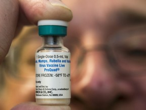 In this Thursday, Jan. 29, 2015 photo, a pediatrician holds a dose of the measles-mumps-rubella (MMR) vaccine at his practice in Northridge, Calif.