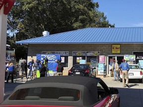 In this Oct. 24, 2018, file photo, media, at left, record people entering the KC Mart in Simpsonville, S.C., after it was announced the winning Mega Millions lottery ticket was purchased at the store.