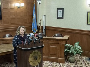 Lewiston City Council President Kristen Cloutier addresses the media in the Lewiston City Council Chambers Friday, March 8, 2019, in Lewiston, Maine, after assuming the role of mayor. At right Shane Bouchard and his wife Allison listen to her remarks moments after Bouchard resigned as mayor of Lewiston. Bouchard resigned in the wake of a controversy over leaked text messages, one of which included a racist remark.