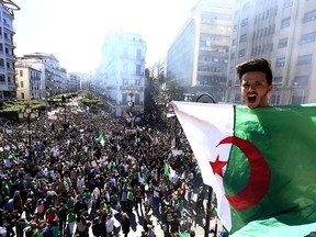 Algerian shouts as he holds the national flag during a protest in Algiers, Algeria, Friday, March 15, 2019. Tens of thousands of people gathered Friday in Algeria's capital and other cities amid heavy security for what could be decisive protests against longtime leader Abdelaziz Bouteflika.