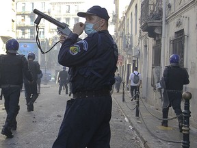 A police officers walks with a teargas rifle during clashes in Algiers, Algeria, March 29, 2019. Algerians taking to the streets for their sixth straight Friday of protests aren't just angry at their ailing president, they want to bring down the entire political system that has sustained him.