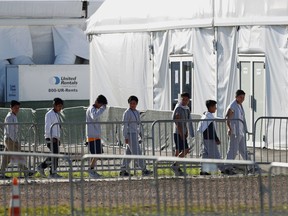 FILE- In this Feb.19, 2019 file photo, children line up to enter a tent at the Homestead Temporary Shelter for Unaccompanied Children in Homestead, Fla. The company that runs the center is Comprehensive Health Services, which is part of Virginia-based Caliburn International Corporation. The chairman of Caliburn International Corp., Thomas J. Campbell, sent a letter Tuesday, March5, to the Securities and Exchange Commission saying it no longer wishes to conduct a public offering.